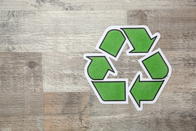 Paper recycling symbol on wooden background, top view. Space for text