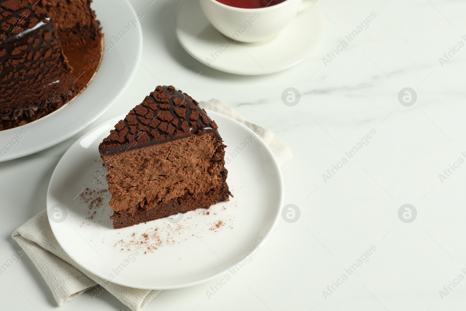 Photo of Piece of delicious chocolate truffle cake on white marble table, space for text