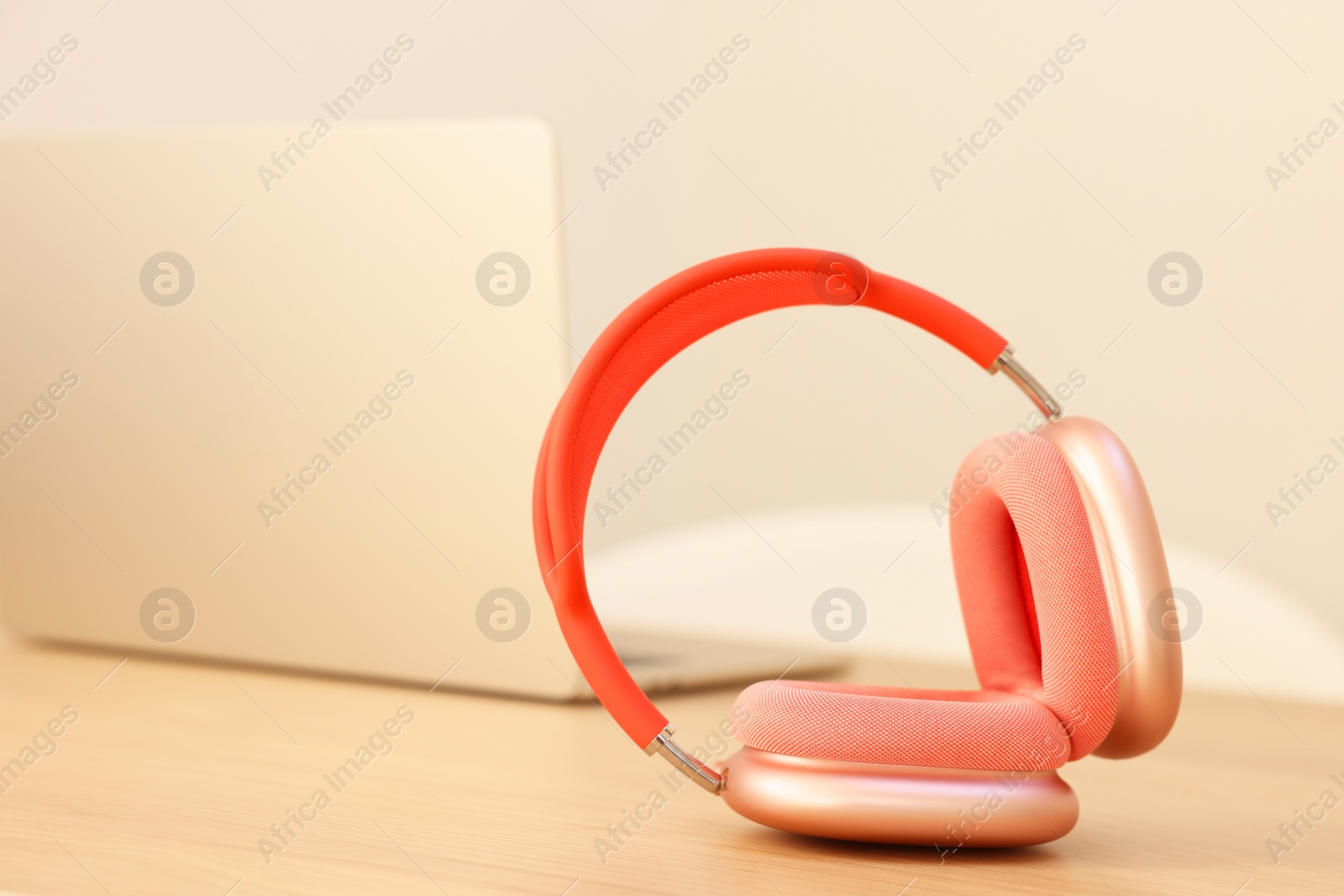 Photo of Modern headphones and laptop on wooden table