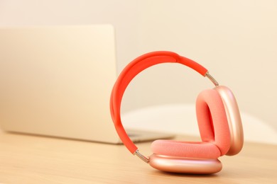 Modern headphones and laptop on wooden table