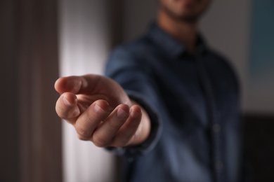 Photo of Man offering helping hand on blurred background, closeup