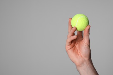 Photo of Man with tennis ball on light grey background, closeup. Space for text