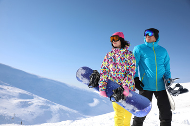 Happy couple with snowboards in mountains. Winter vacation