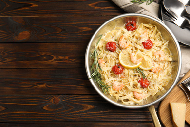 Photo of Delicious pasta with shrimps served on wooden table, flat lay. Space for text