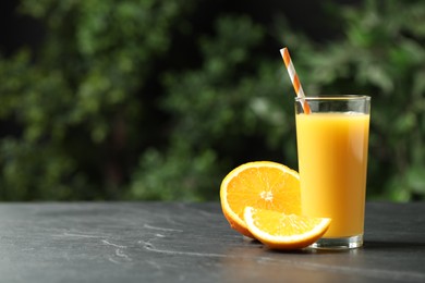 Photo of Glass of orange juice and fresh fruits on grey table. Space for text