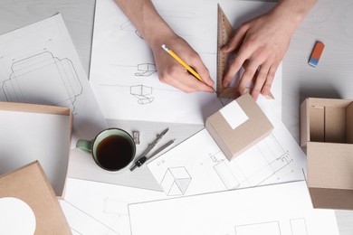 Photo of Man creating packaging design at light wooden table, top view