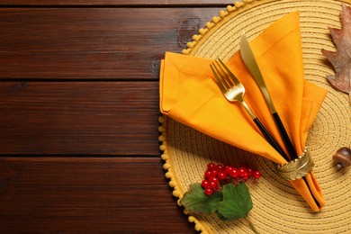 Photo of Autumn table setting. Cutlery, napkin and viburnum berries on wooden background, top view with space for text