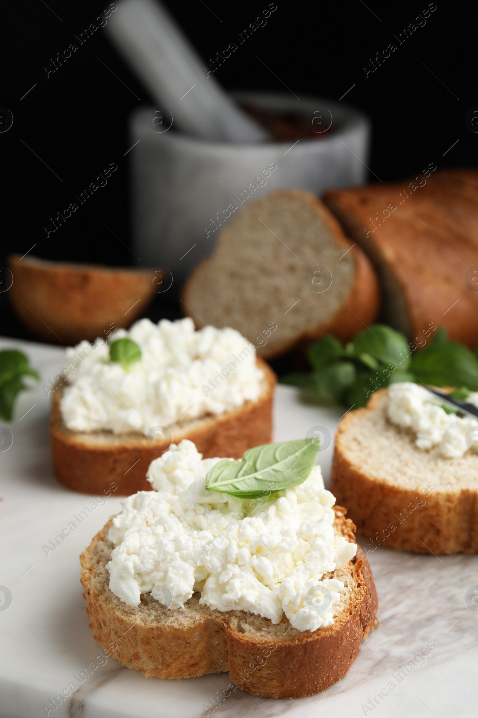 Photo of Bread with cottage cheese and basil on board, closeup