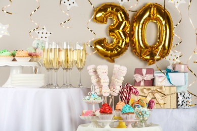 Photo of Dessert table in room decorated with golden balloons for 30 year birthday party