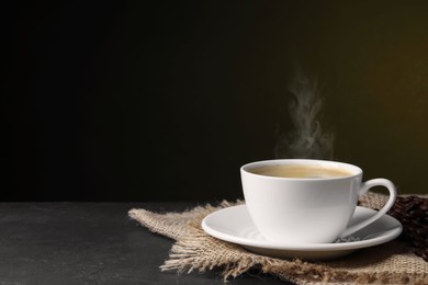 Image of Steaming coffee in cup and roasted beans on table. Space for text