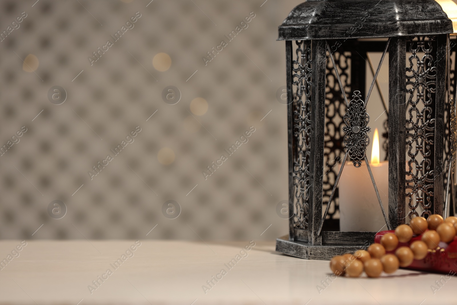 Photo of Arabic lantern, Quran and misbaha on white table. Space for text