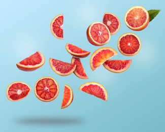 Image of Many cut tasty Sicilian oranges falling on light blue background