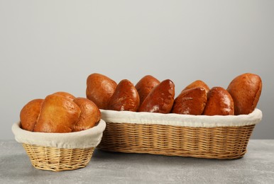 Photo of Delicious baked patties in wicker baskets on light grey table
