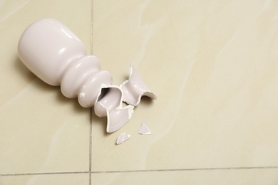 Broken pink ceramic vase on floor. Space for text