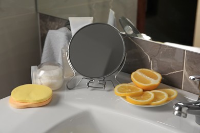 Photo of Lemon face wash. Fresh citrus fruits, personal care products and mirror on sink in bathroom