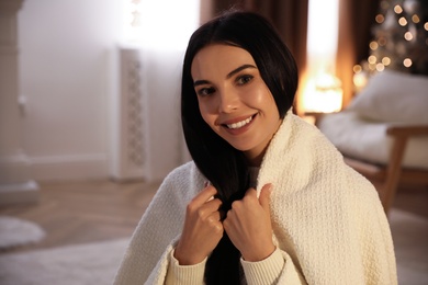 Beautiful woman covered in white plaid at home