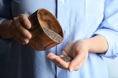 Photo of Woman pouring chia seeds from bowl into hand, closeup