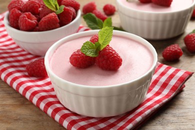 Photo of Delicious raspberry mousse with mint on wooden table