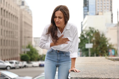 Photo of Young woman having heart attack on city street