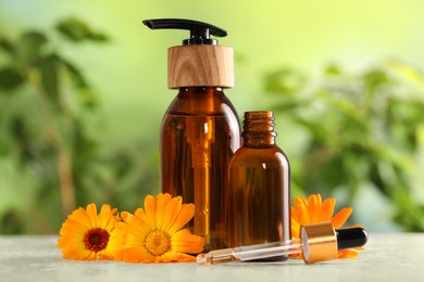 Photo of Bottles of essential oils and beautiful calendula flowers on white table outdoors, closeup