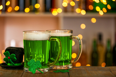 Photo of Green beer, clover and hat on wooden counter, closeup. St.Patrick's Day celebration