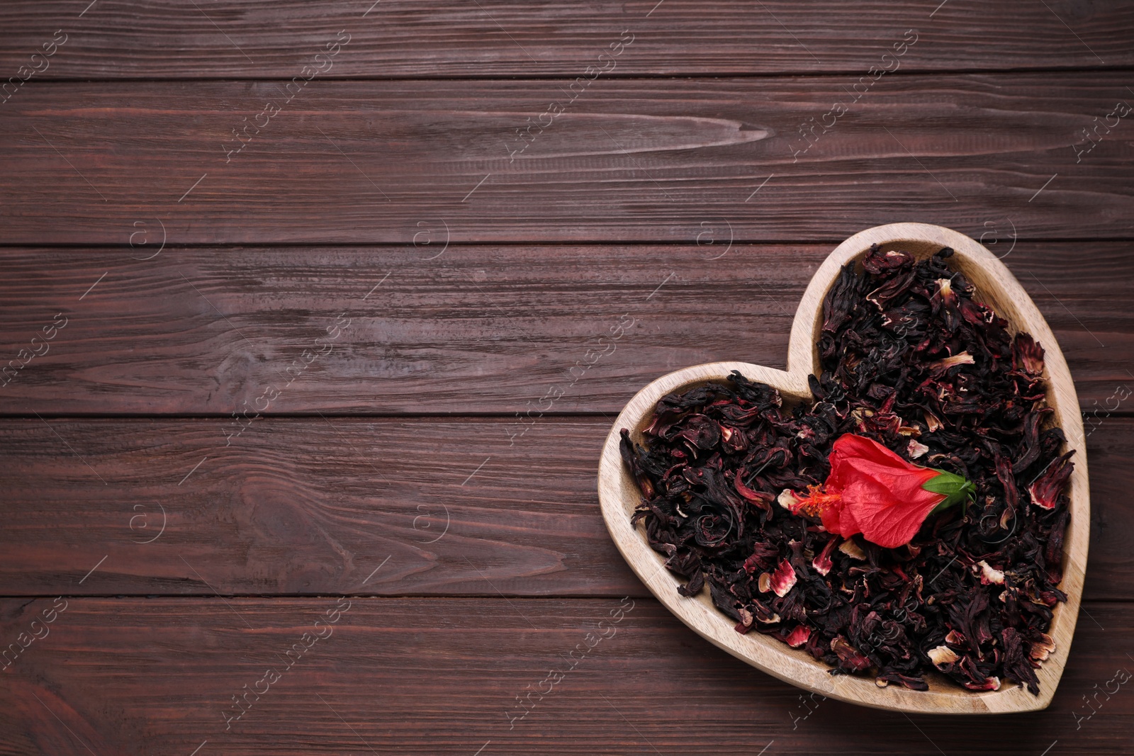 Photo of Dry hibiscus tea and flower on wooden table, top view. Space for text