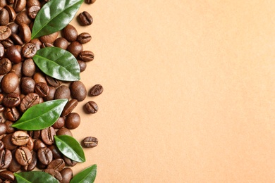 Fresh green coffee leaves and beans on light orange background, flat lay. Space for text