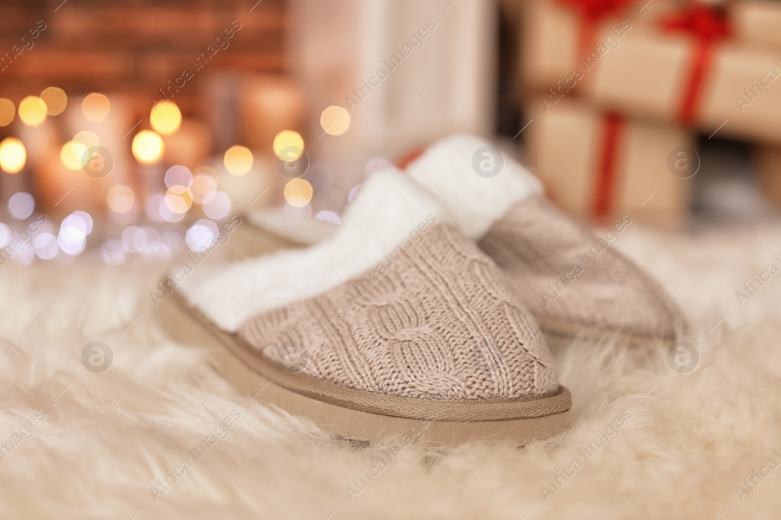 Photo of Soft slippers, fuzzy rug and blurred Christmas lights on background