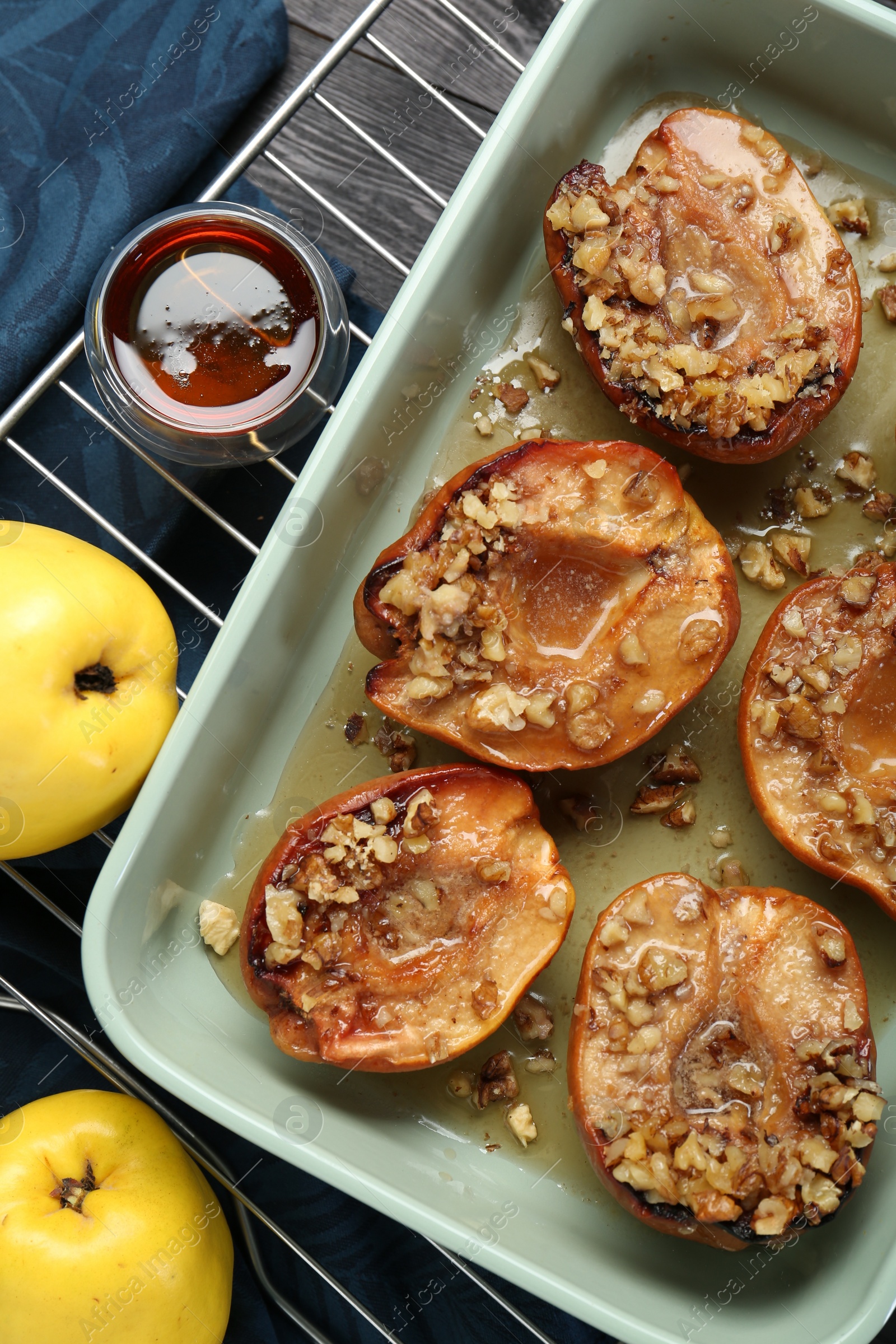 Photo of Tasty baked quinces with nuts and honey in dish on table, flat lay