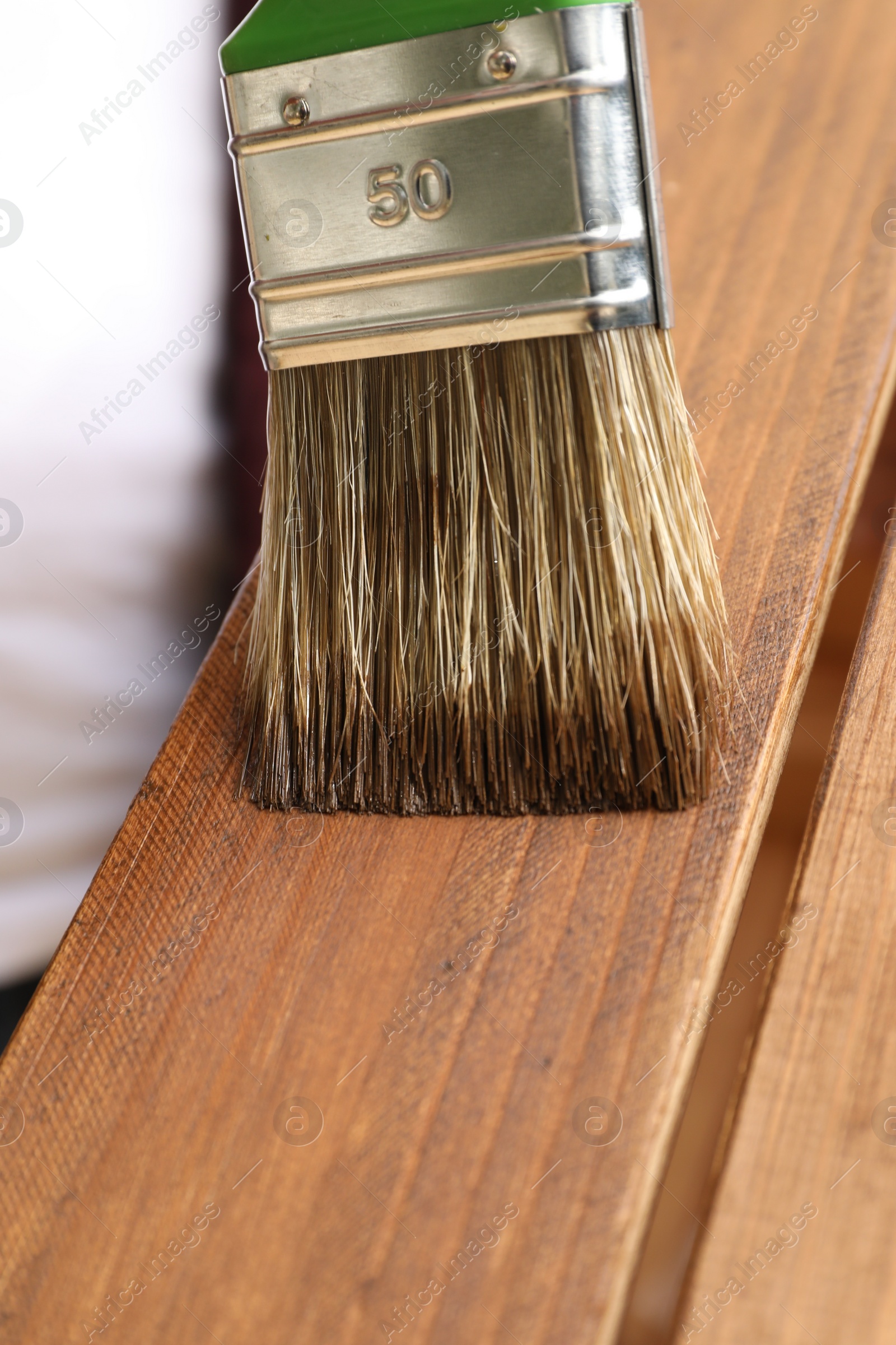 Photo of Applying wood stain onto wooden surface, closeup view