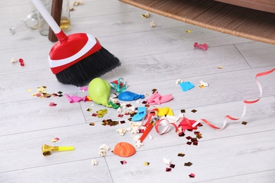 Photo of Sweeping trash after party with bristle broom indoors