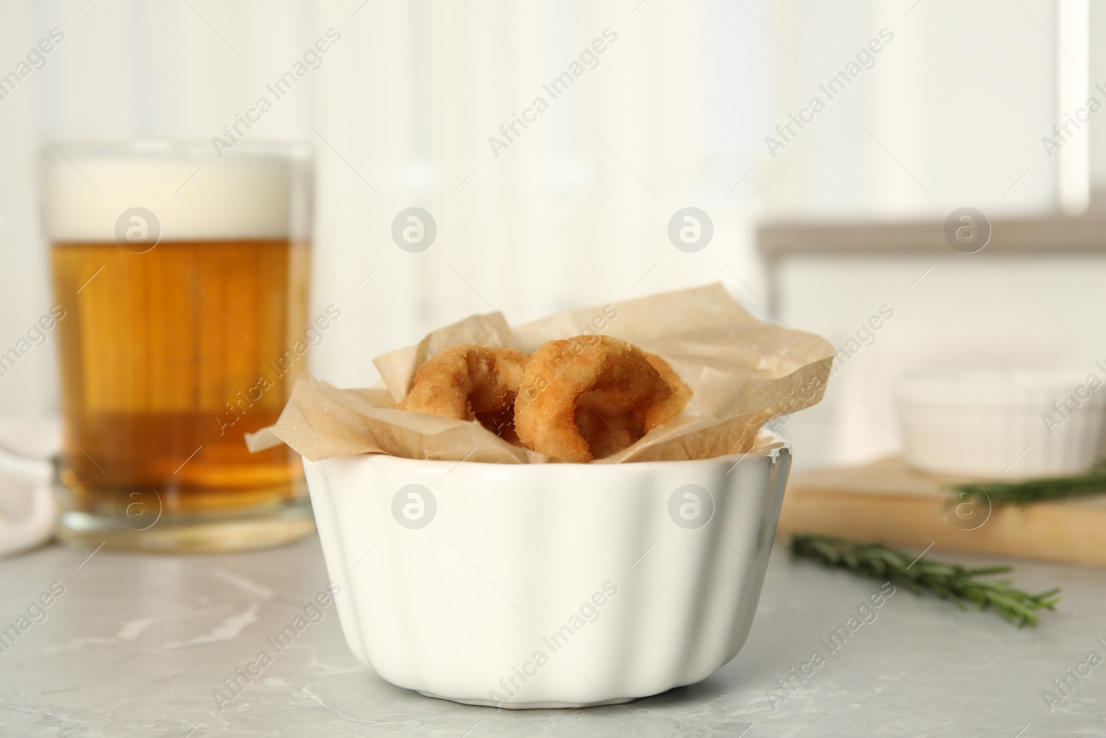 Photo of Delicious crunchy fried onion rings on grey marble table indoors