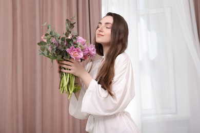 Photo of Beautiful young woman with bouquet of flowers indoors