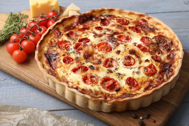 Photo of Delicious homemade prosciutto quiche and ingredients on gray wooden table, closeup