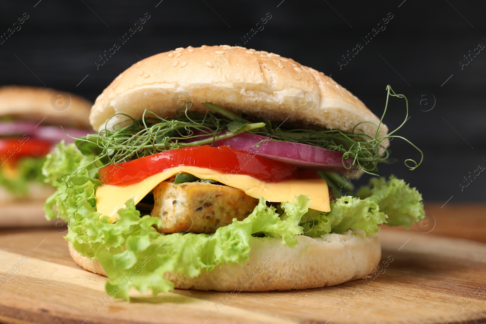 Photo of Delicious burger with tofu and fresh vegetables on wooden table, closeup