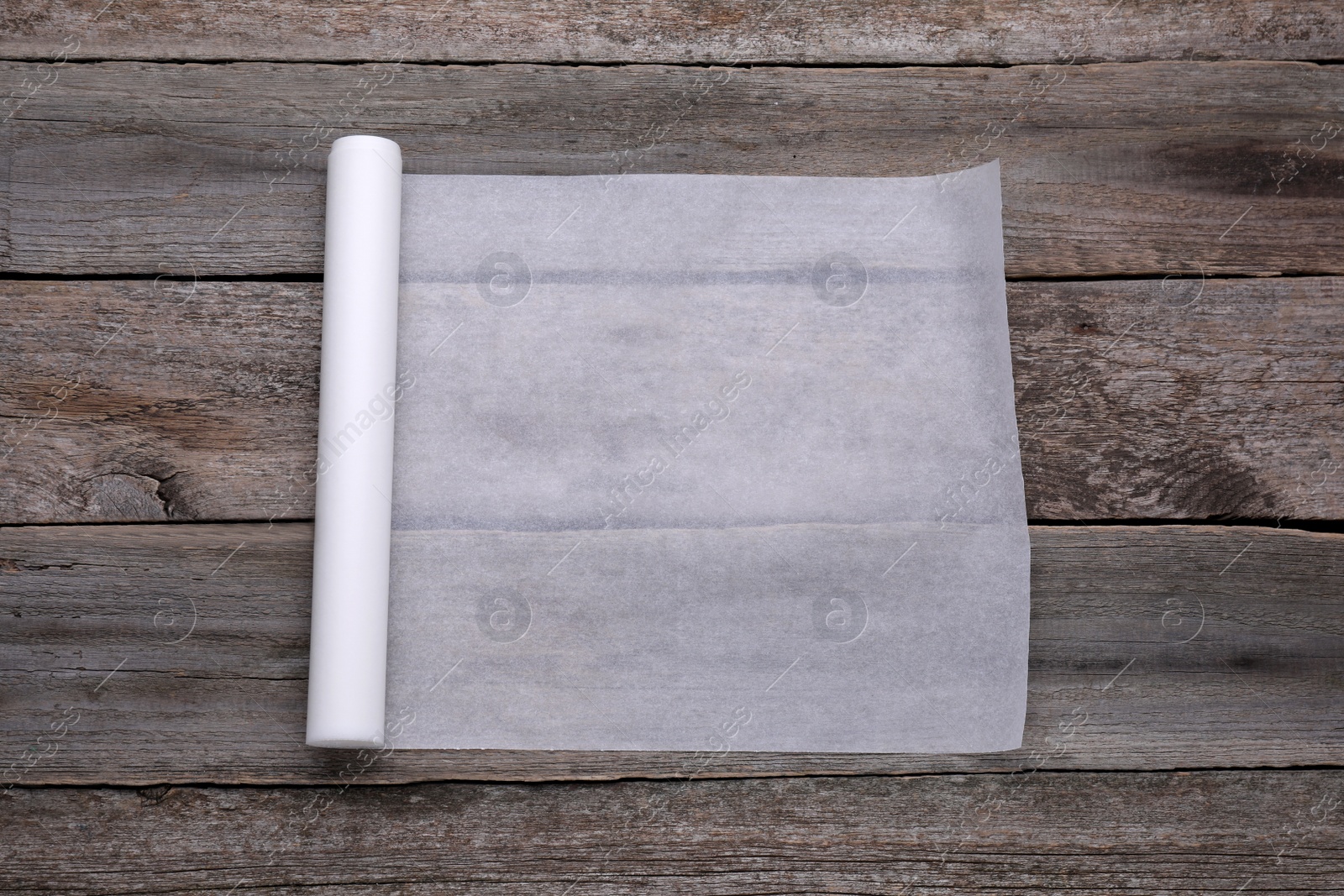 Photo of Roll of baking paper on wooden table, top view