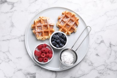 Photo of Delicious Belgian waffles with fresh berries and powdered sugar on white marble table, top view