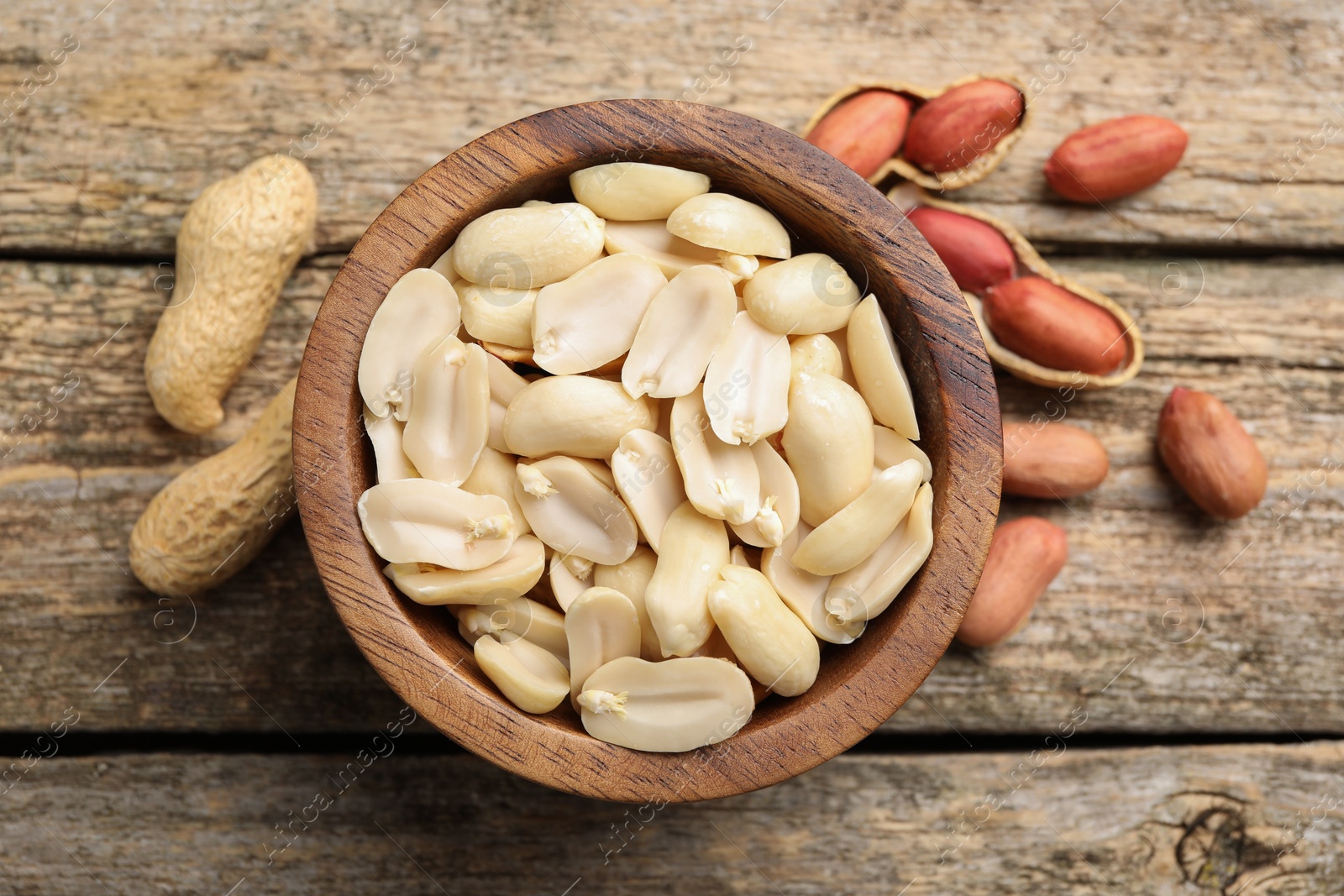 Photo of Fresh peanuts in bowl on wooden table, top view
