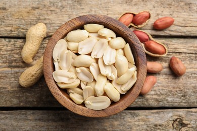 Fresh peanuts in bowl on wooden table, top view