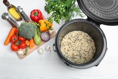 Modern multi cooker and products on white wooden table, flat lay