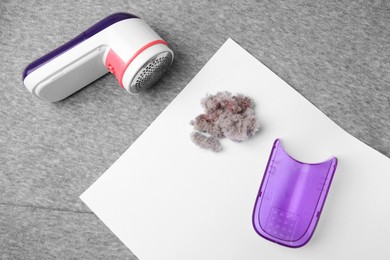 Photo of Modern fabric shaver and lint on light grey cloth, flat lay