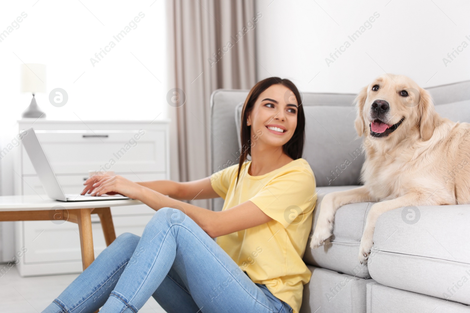 Photo of Young woman and her Golden Retriever dog in living room