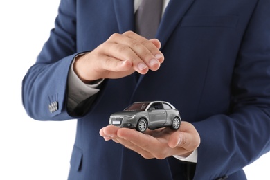 Photo of Insurance agent holding toy car on white background, closeup