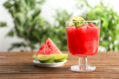 Tasty summer watermelon drink in glass and sliced fruit on table