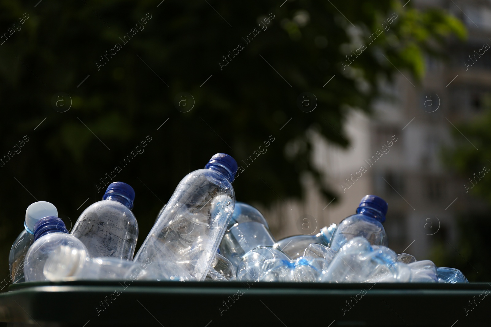 Photo of Many used plastic bottles in trash bin outdoors, closeup. Recycling problem