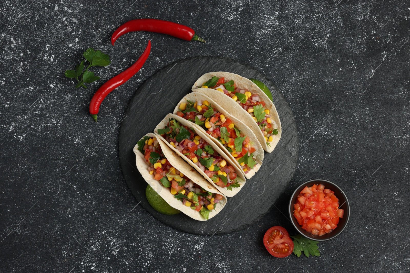 Photo of Tasty tacos with vegetables on black textured table, flat lay