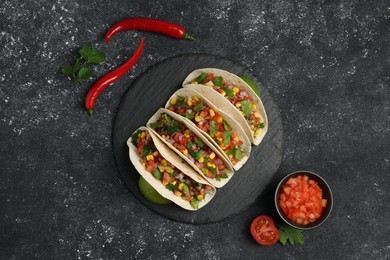 Photo of Tasty tacos with vegetables on black textured table, flat lay