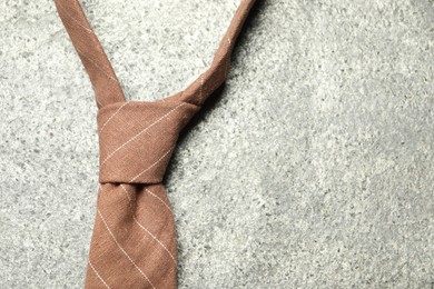 Photo of One striped necktie on grey textured background, top view. Space for text
