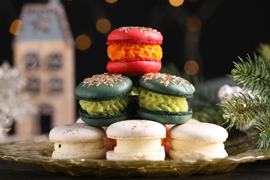 Photo of Beautifully decorated Christmas macarons and fir branches against blurred lights