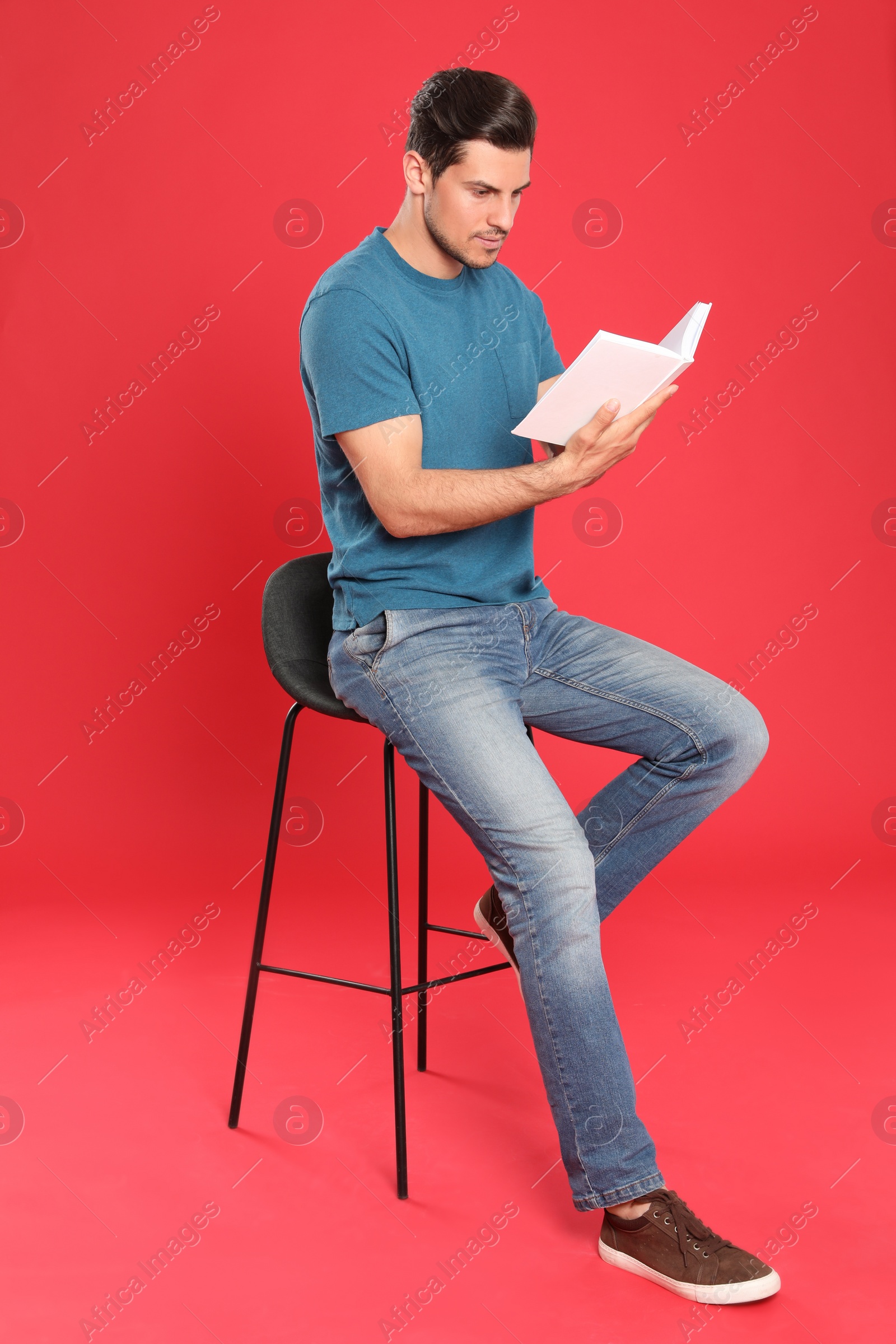 Photo of Handsome man reading book on color background